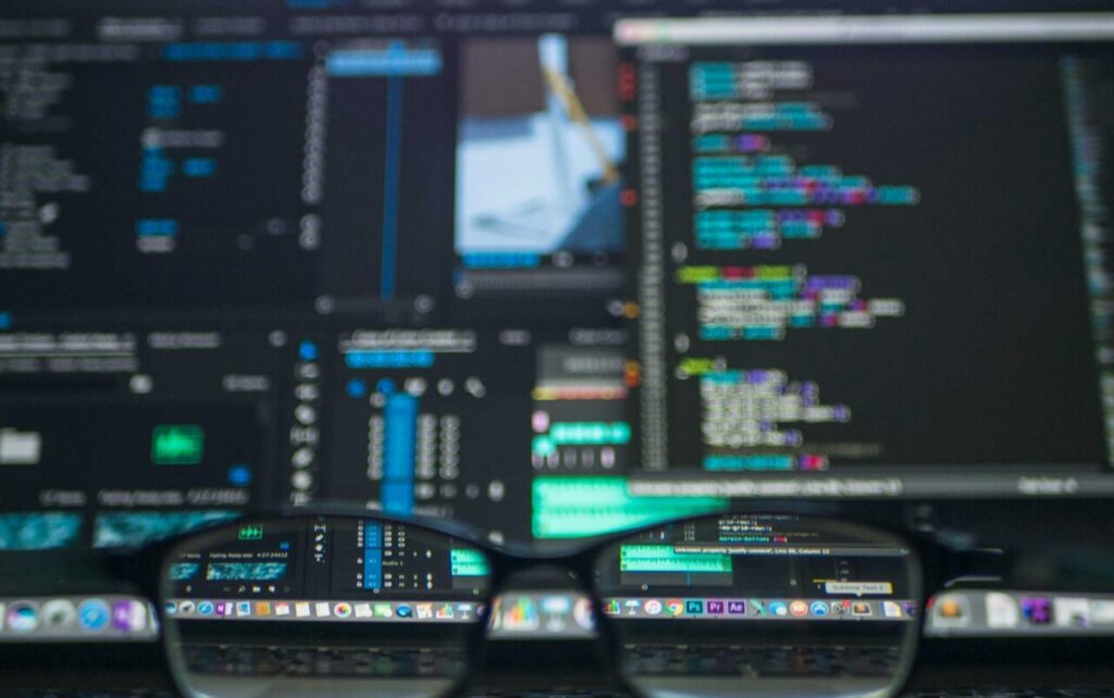 Eyeglasses reflecting computer code on a monitor, ideal for technology and programming themes.