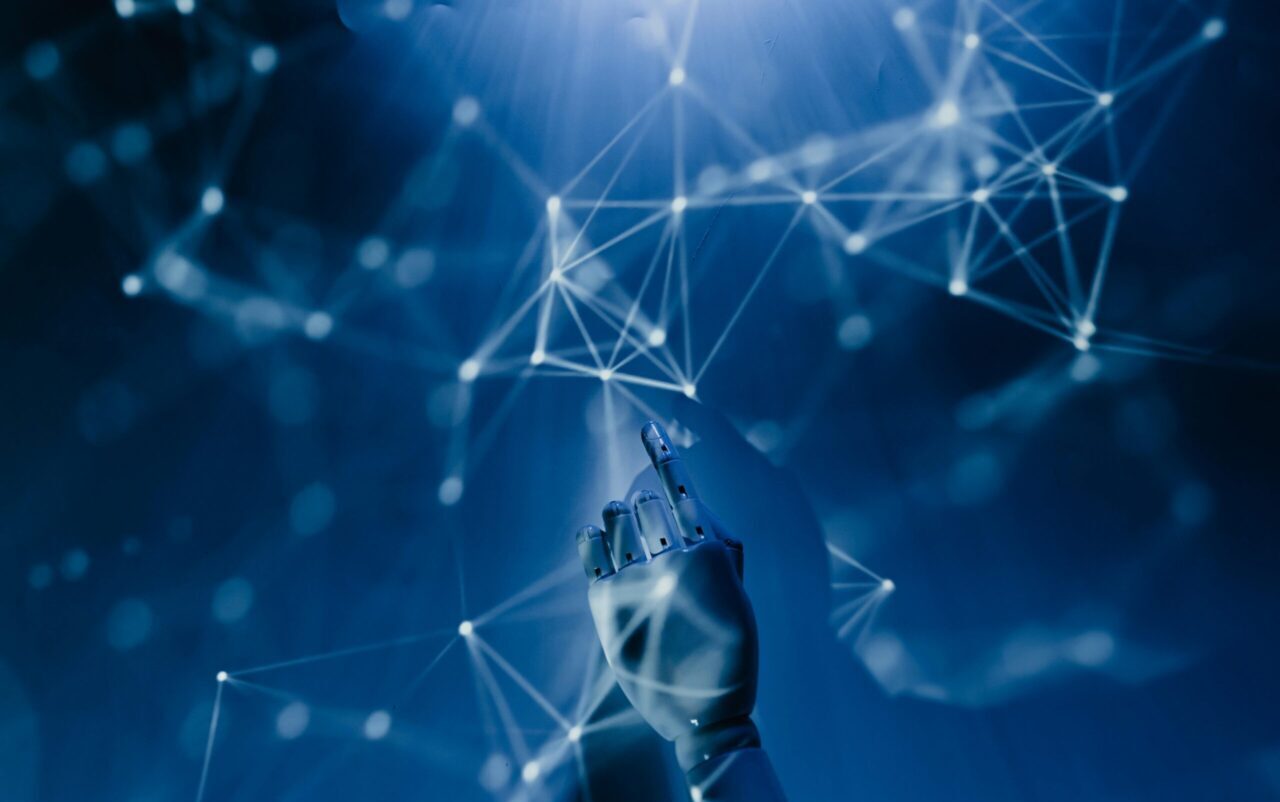 A robotic hand reaching into a digital network on a blue background, symbolizing AI technology.