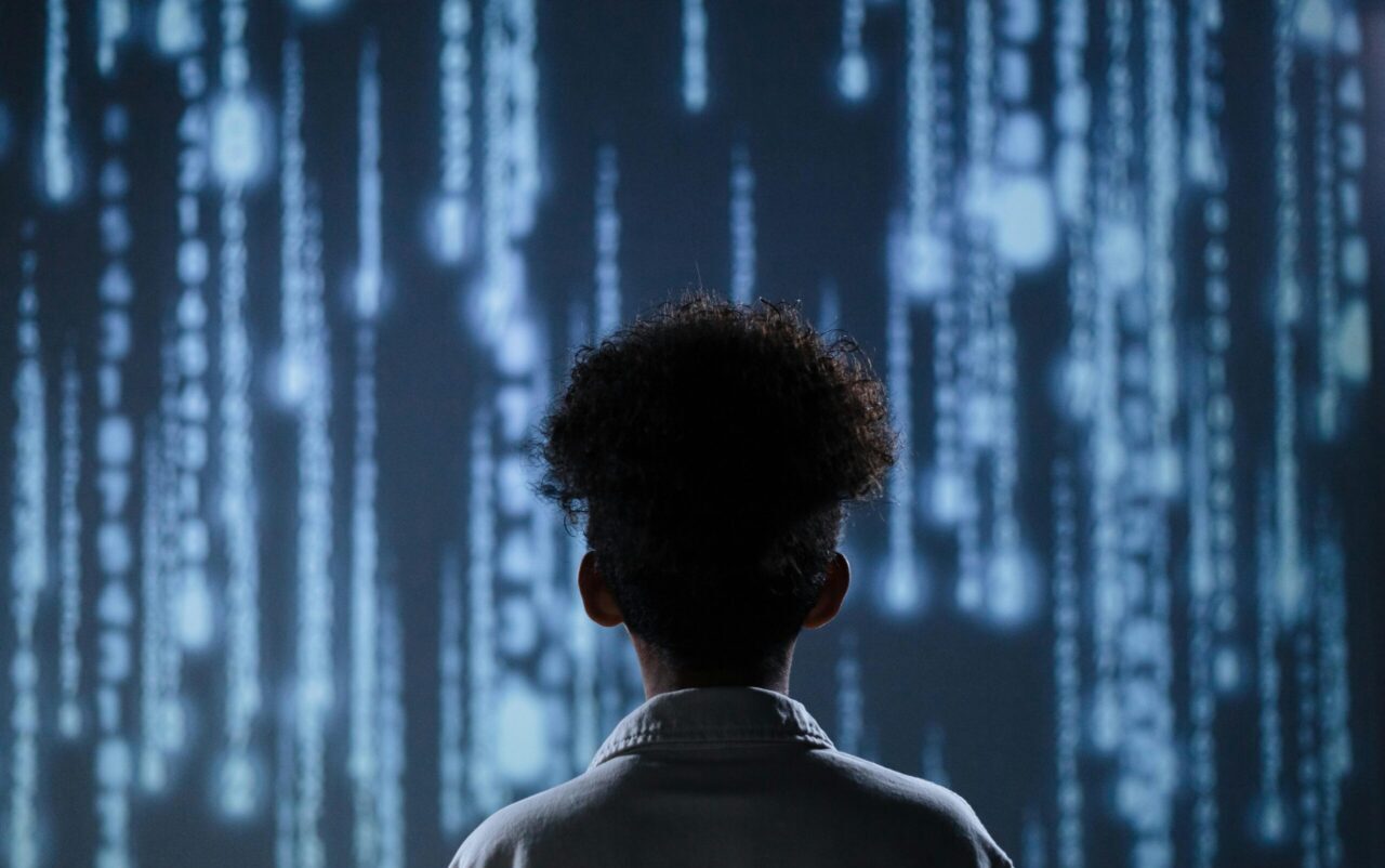 A young boy viewing a digital screen with data streams, symbolizing technology interaction.